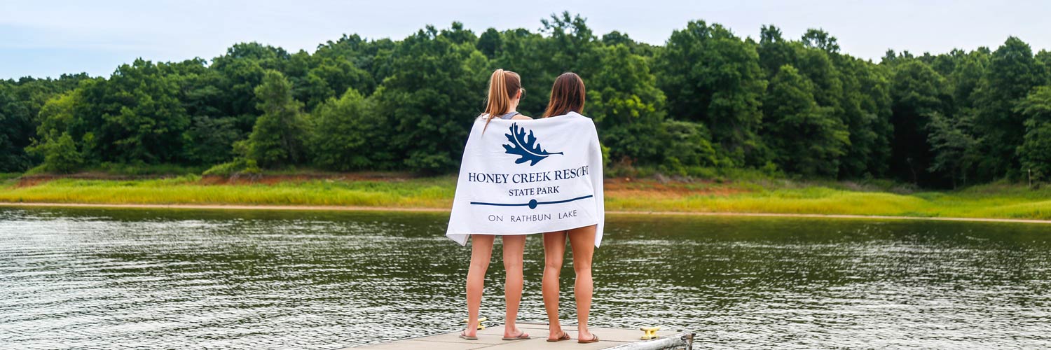 Girls wrapped in a Honey Creek Resort towel standing at the dock on Rathbun Lake