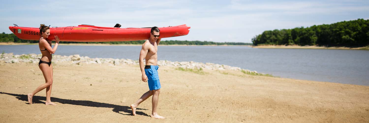 Couple walking a rental kayak down to the beach at Honey Creek Resort