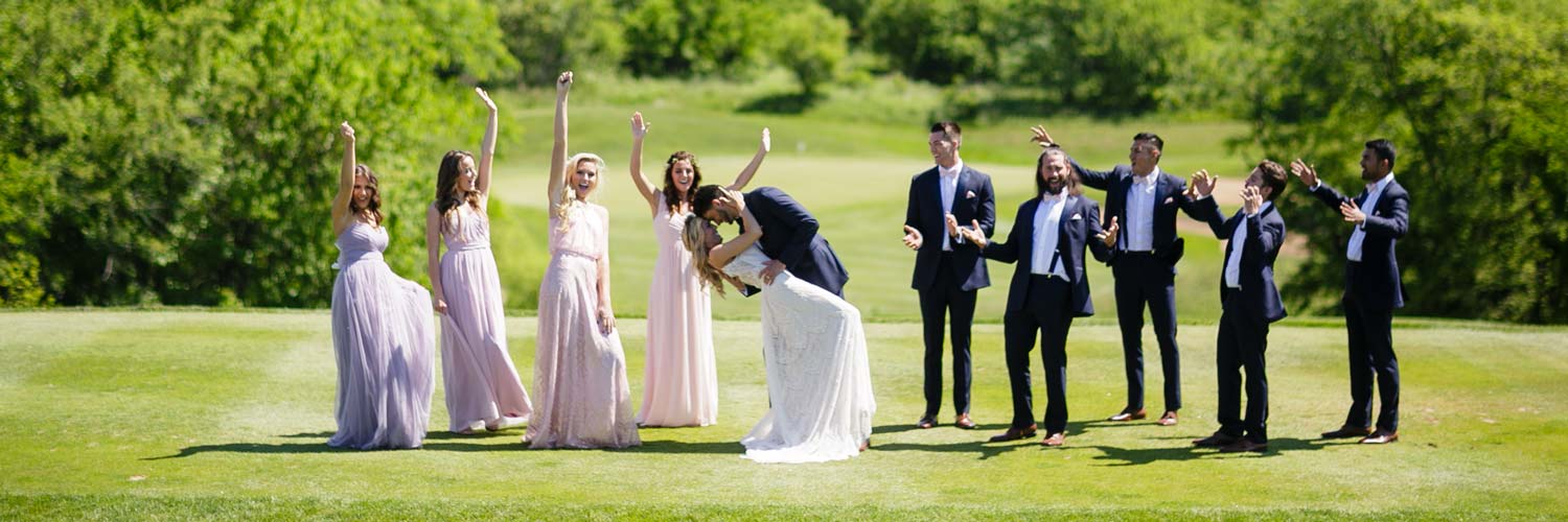 Wedding party celebrates the bride and groom on the lawn at Honey Creek Resort in Iowa