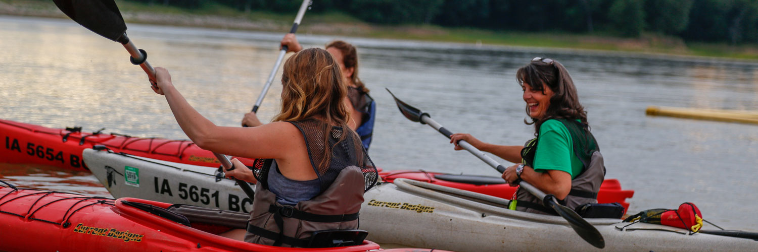 Three guests kayak at sunset at Honey Creek Resort