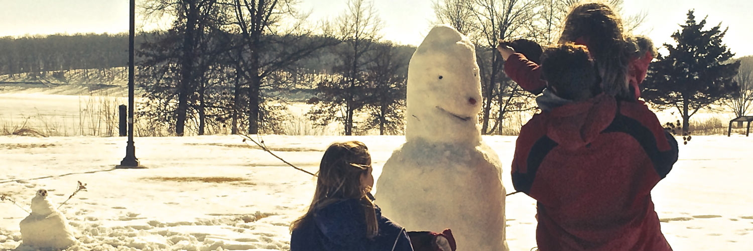 A family builds a snowman together