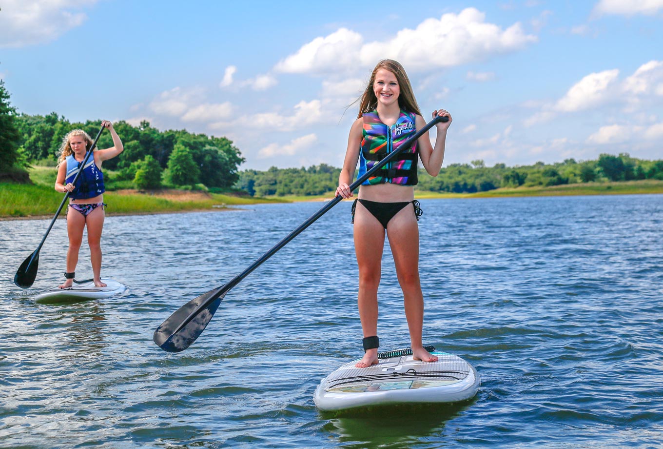 Girls enjoy stand-up paddleboarding on Rathbun Lake with SUP rentals from Honey Creek Resort