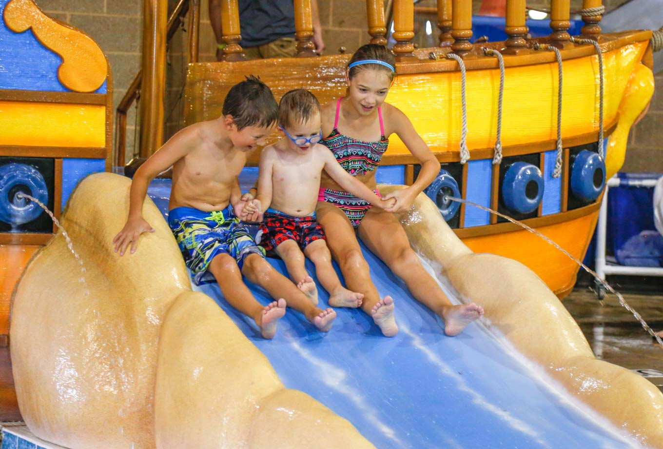 Three kids ready to slide into the water at the indoor water park, Bucanneer Bay, at Honey Creek Resort