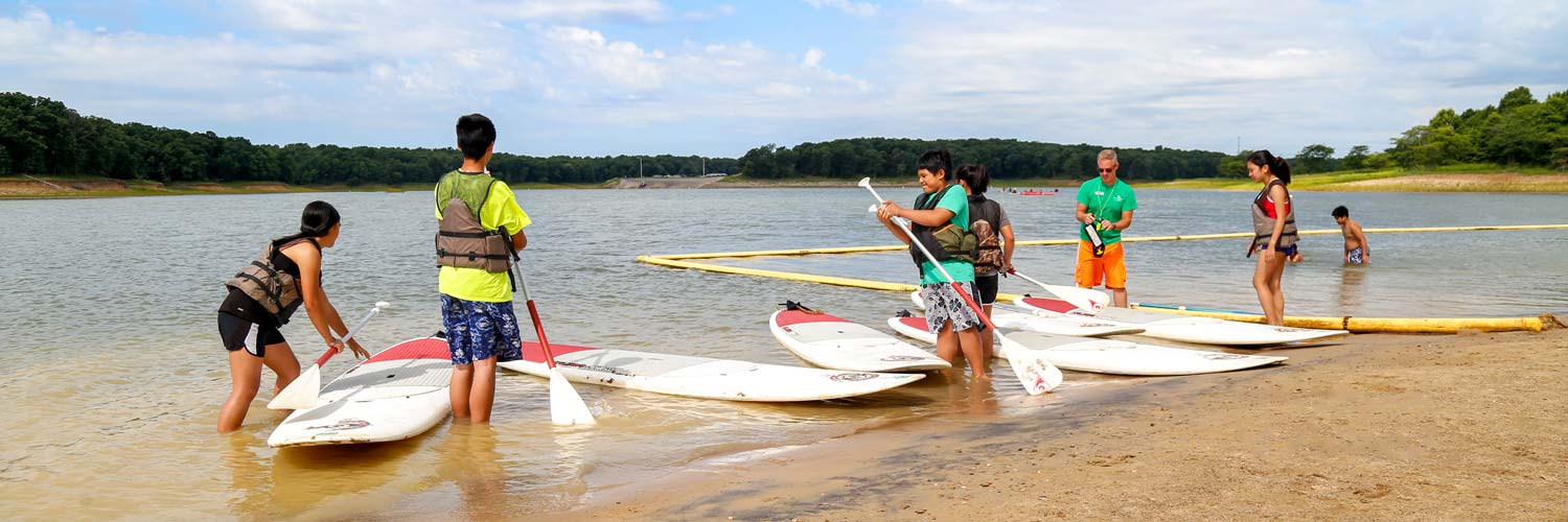 A group of friends get ready to use stand up paddleboards on Rathbun Lake