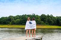 Two girls hold Honey Creek Resort towels on the marina docks at Rathbun Lake