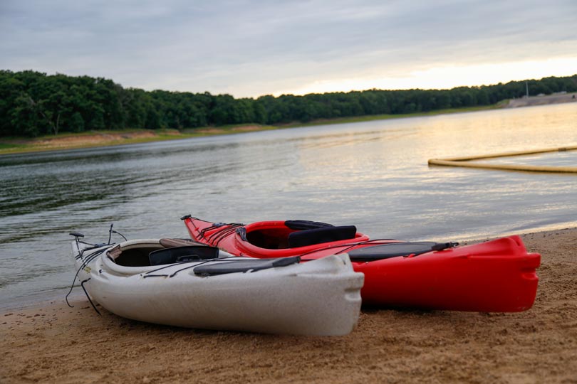 Kayak rentals from Honey Creek Resort are placed near the Rathbun Lake shoreline