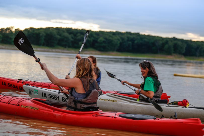 A group of people take a kayaking class at sunset together on Rathbun Lake at Honey Creek Resort