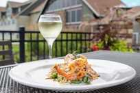 Delicious dining option featuring shrimp served outdoors with a glass of white wine at Rathbun Lakeshore Grille restaurant at Honey Creek Resort