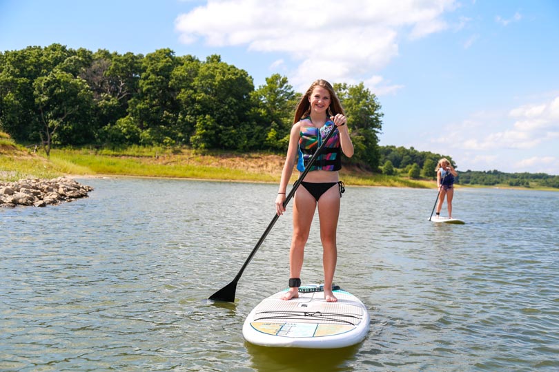 Girls enjoy stand-up paddleboarding on Rathbun Lake with SUP rentals from Honey Creek Resort