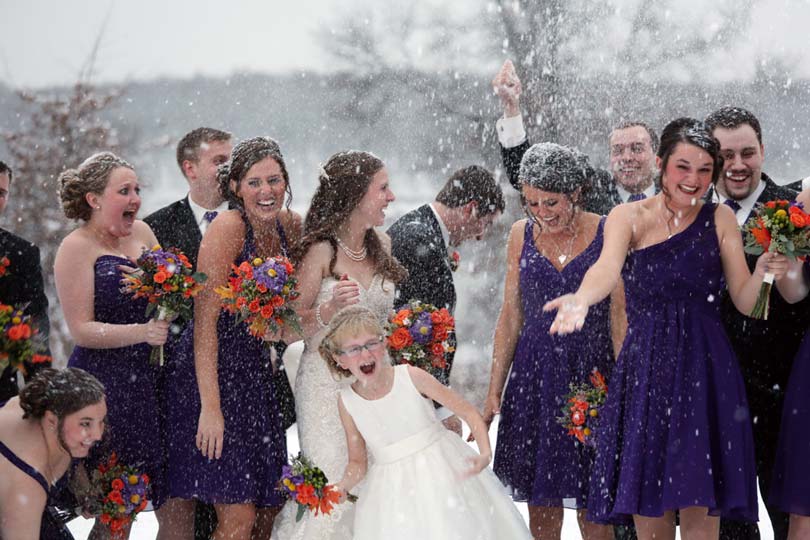 Winter wedding bridal party taking pictures in the snow at Honey Creek Resort