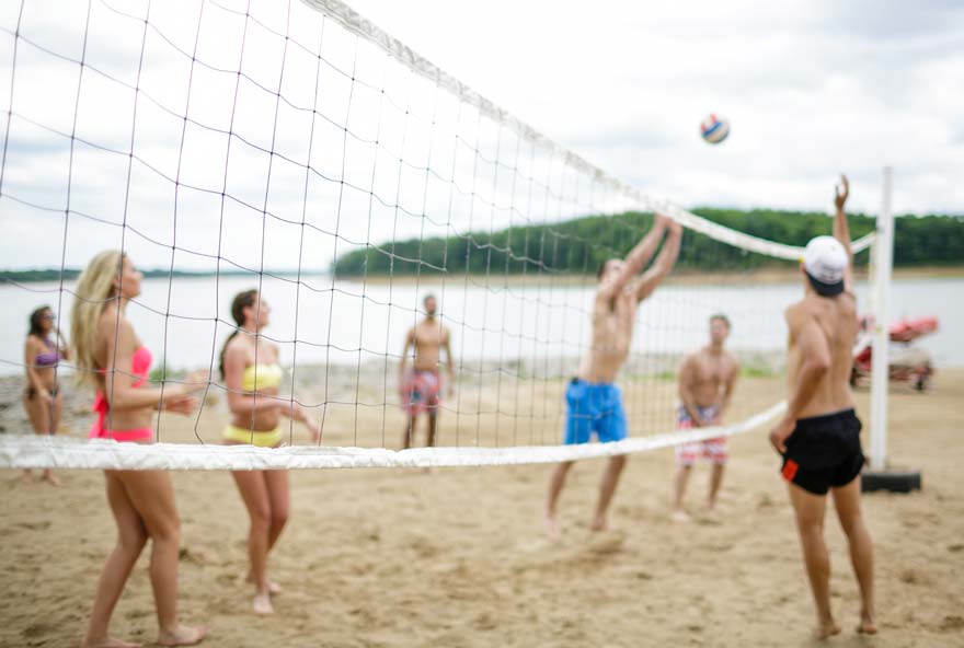 Group of friends playing volleyball on the beach at Honey Creek Resort