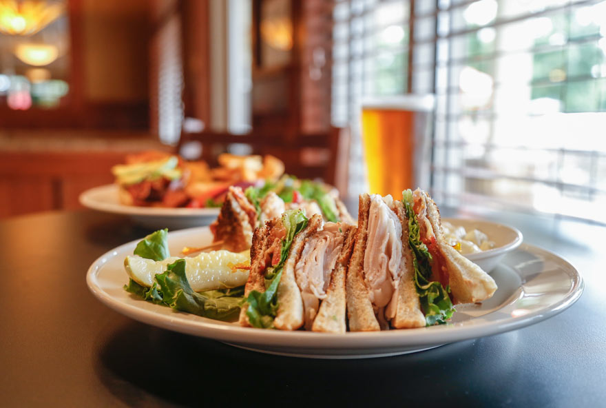 A club sandwich is served on a plate at Rathbun Lakeshore Grille at Honey Creek Resort