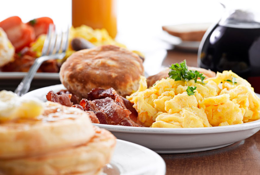 A delicious breakfast plate of scrambled eggs, bacon, and biscuits