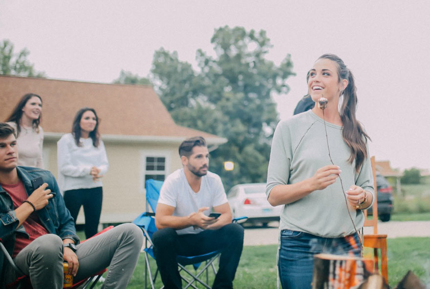 A group of friends make s'mores outside of a cottage at Honey Creek Resort