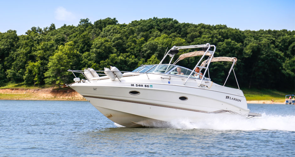 Two men in a boat on Rathbun Lake with trees in the background