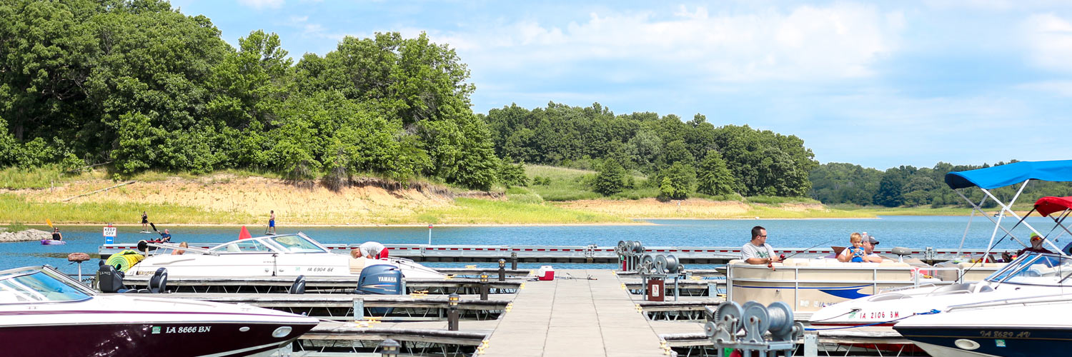 A marina with pontoons and other boats is shown on Rathbun Lake at Honey Creek Resort