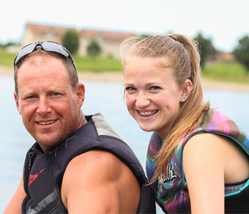Father and daughter sitting on a jet ski wearing life jackets
