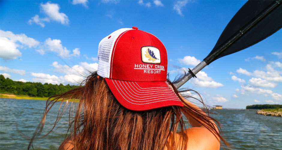 Girl wearing red hat with Honey Creek Resort logo holding a paddle