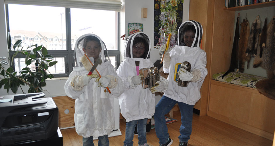 Three children wearing beekeeper suits